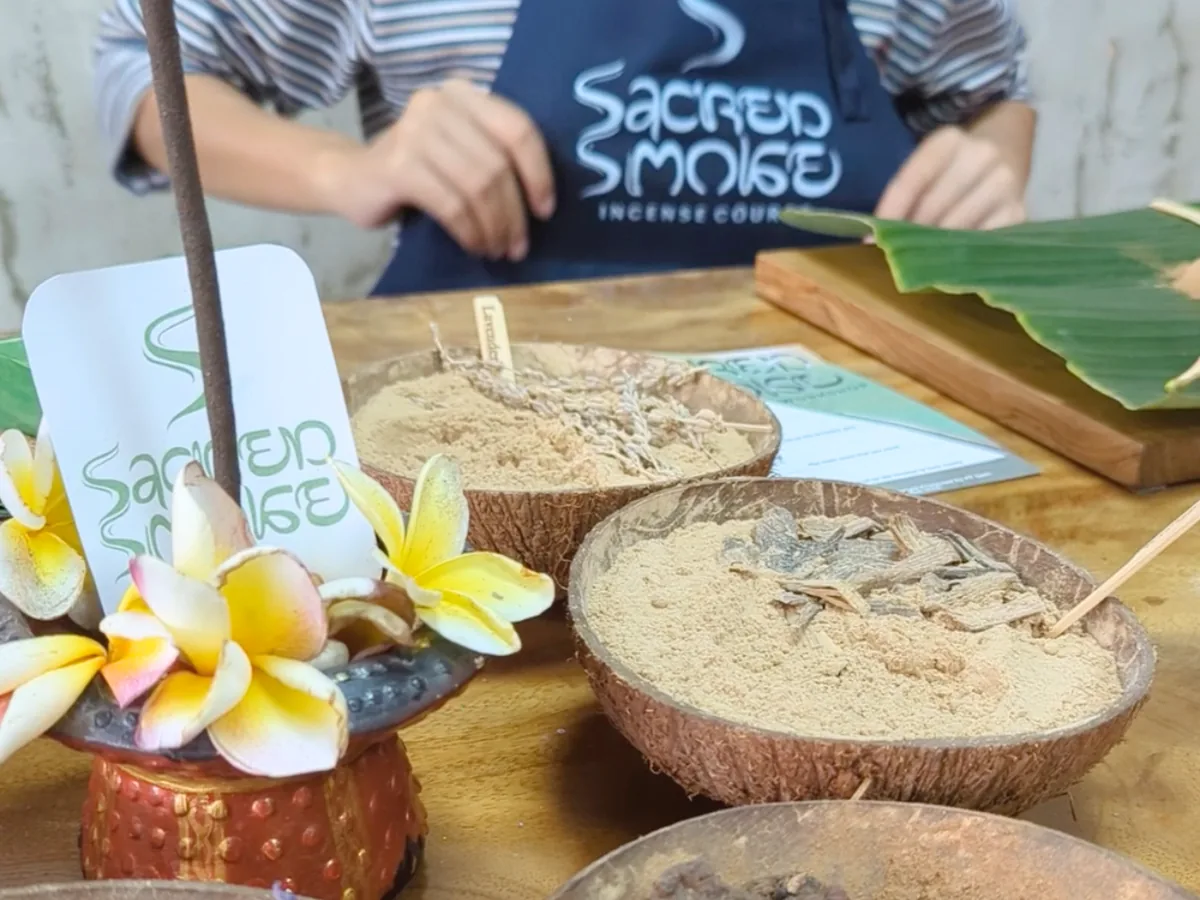 Sacred Smoke apron behind bowls of raw incense botanicals and workshop materials